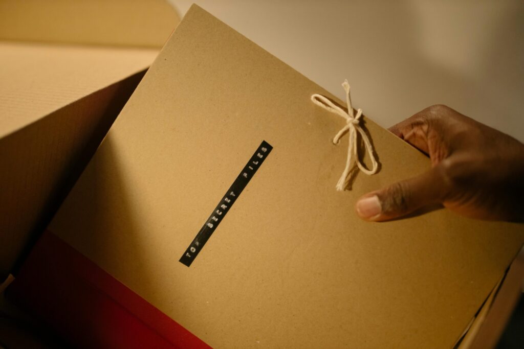 Close-up of hand holding top secret document folder in a box.